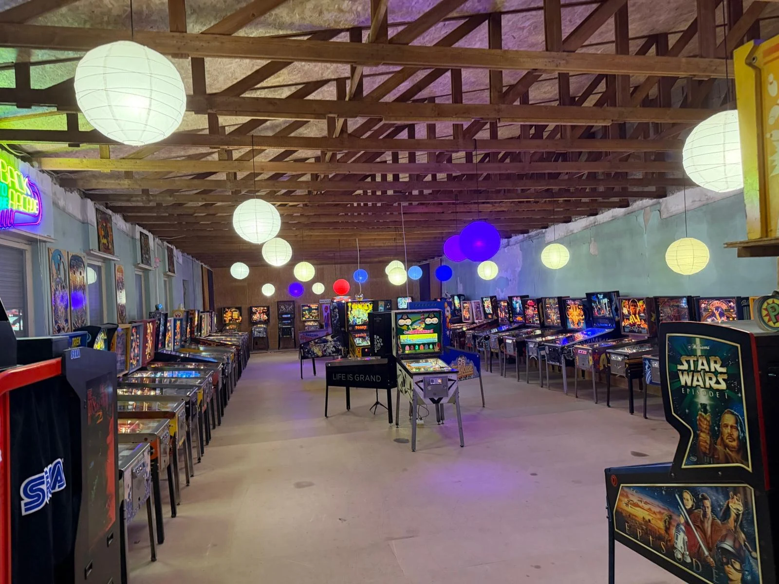 Großer Flipperloft Showroom mit vielen beleuchteten Flipperautomaten